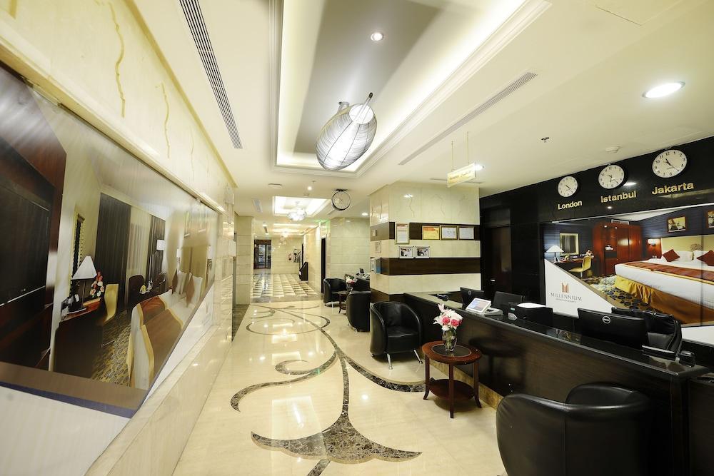 Al Aqeeq Madinah Hotel Medína Exteriér fotografie The photo shows the interior of a hotel lobby or reception area. It features a sleek, modern design with elegant marble flooring, decorative lighting fixtures on the ceiling, and a sophisticated color scheme. There are comfortable black seating areas