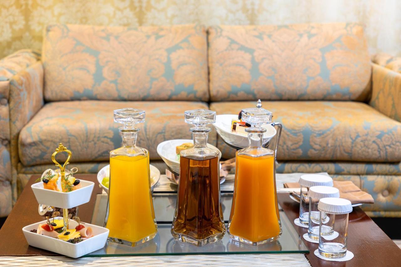 Al Aqeeq Madinah Hotel Medína Exteriér fotografie The photo features a beautifully arranged table with several glass decanters filled with liquids. Two decanters, one containing a yellow drink (possibly juice) and another with a darker beverage (possibly tea), are placed prominently. In front of the