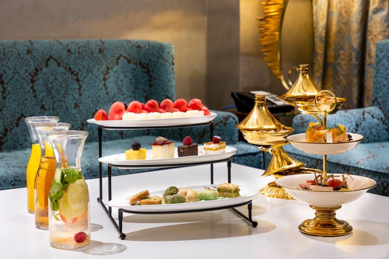 Al Aqeeq Madinah Hotel Medína Exteriér fotografie The photo displays an elegant dessert arrangement on a table. There are two levels of desserts: 

1. **Top Tier**: Features a selection of colorful sweets, including layers of cream or mousse desserts, garnished with fresh berries.
2. **Bottom Tier**