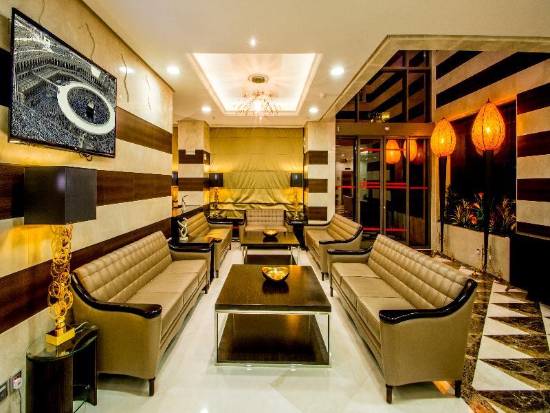 Al Aqeeq Madinah Hotel Medína Exteriér fotografie The photo shows a modern and stylish living area or lounge. It features several beige leather sofas arranged around a central black coffee table. The walls are decorated with a mix of light colors and dark wooden accents. There is a large flat-screen