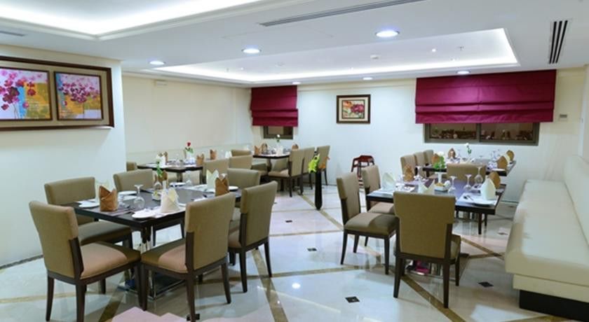 Al Aqeeq Madinah Hotel Medína Exteriér fotografie The photo shows a well-decorated restaurant interior. It features several tables arranged neatly throughout the space, each set with chairs and tableware, including plates, glasses, and napkins. The flooring is a polished stone surface with a stylish