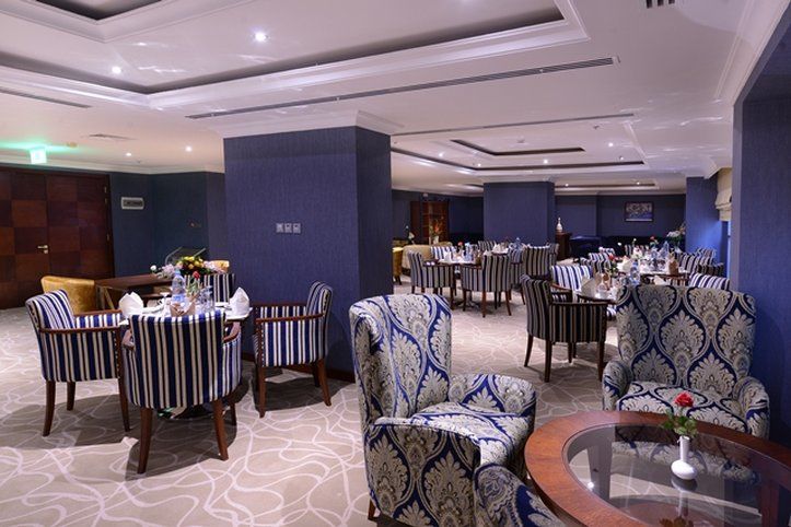 Al Aqeeq Madinah Hotel Medína Exteriér fotografie The photo shows an elegant dining or lounge area. The space features plush seating with striped and patterned chairs, and tables set up for dining. The decor includes a rich color palette with blue walls and soft lighting creating a warm atmosphere. 